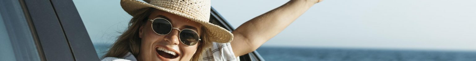 happy-blonde-woman-with-hat-looking-out-car-window